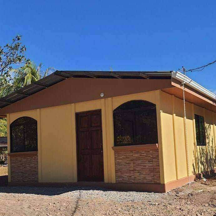Casa color arena con ventanas en arco y zócalo de piedra, entregada en La Unión, Cartago