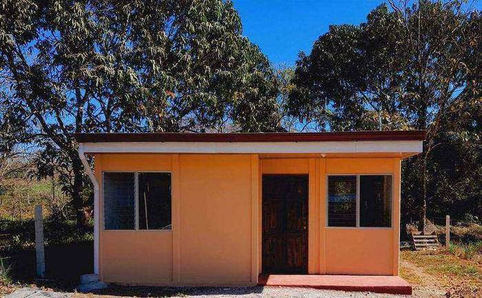 Casa naranja de una planta con puerta de madera, entregada en Esparza, Puntarenas